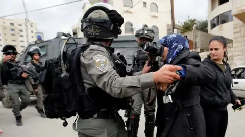 Reuters A local photographer takes pictures as an Israeli border police member holds her back during the demolition of a Palestinian house whose owners said they were informed by the Israeli forces that they didn't obtain a construction license, in Beit Jala in the Israeli-occupied West Bank on 2 April 2019.