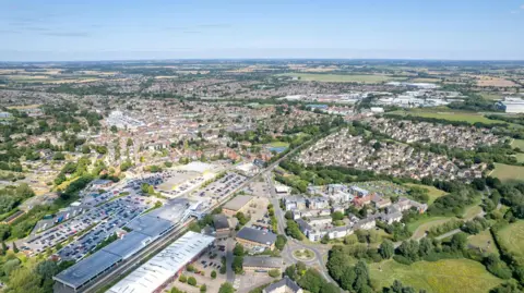 A bird's eye view of Bicester, including the Bicester Village shopping centre at the bottom of the picture, and fields surrounding the town