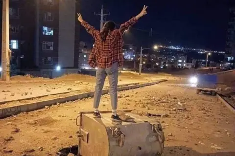 Twitter Photo posted online reportedly showing a young woman stands on a dumpster on a street in Sanandaj, western Iran, during an anti-government protest