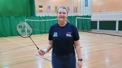 Lesley Miller holding a badminton racket and wearing her team Great Britain tracksuit.