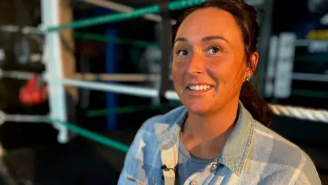 Emma Baugh/BBC Amy wearing a blue checked denim shirt