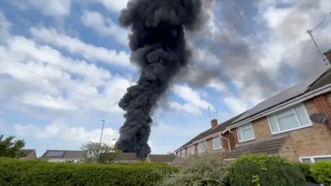 Smoke billows into the sky from an industrial estate fire.