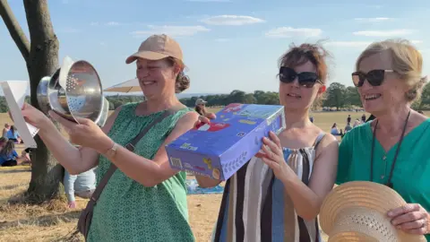 Dan Bater/BBC Three women: one with a colander and some paper and another with a cereal box.
