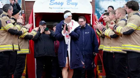 PA Media Firefighters form a guard of honour to applaud Kevin Sinfield, as he comes out of the players' tunnel at Craven Park on day five of his fundraising run.