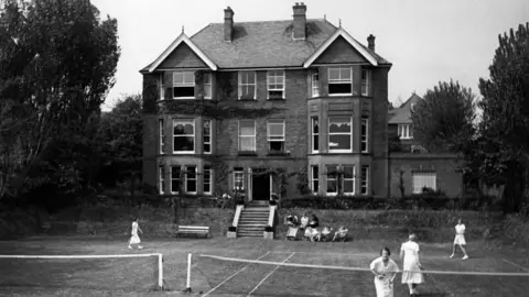 Getty Images A black and white photo of the Augusta Victoria College. There are students playing at the tennis court.