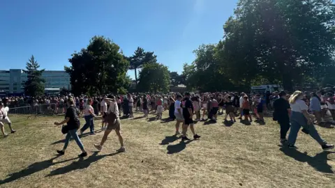 Alice Cunningham/BBC Hundreds of fans stand and walk in Alderman Park in the sunshine.