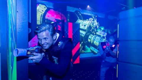 Holding Laser Tag weapons father and son Jeff and Freddy Brazier play the game