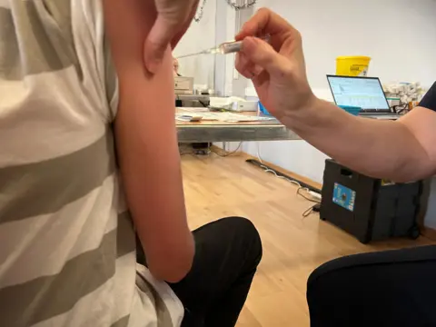 Emma Baugh/BBC Vaccination clinic with someone receiving an injection