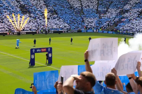 Getty Images Thousands of fans are seen holding up the signs at the CBS Arena after beating Wrexham 