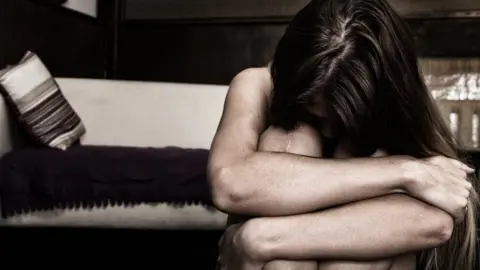 Getty Images Woman hugging her knees