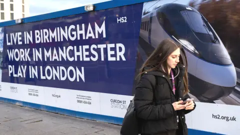 Woman walks past HS2 sign