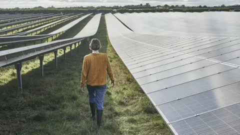 Mike Harrington/Getty Young farmer walking through her solar farm