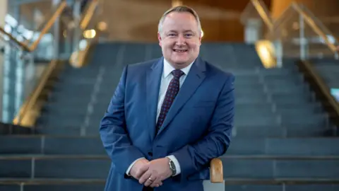 Getty Images Darren Millar leaning on a banister on a set of steps of the Senedd in Cardiff Bay