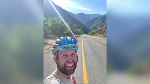 Simon Watts Simon Watts smiles for a photo on a rural road.