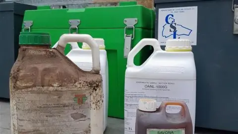 Four pesticide bottles - two white, one white but with dirt and mould and another clear with brown liquid inside.