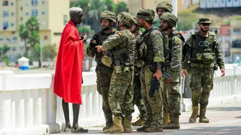 Spanish soldiers question a migrant, following mass crossings of migrants on foot and by sea