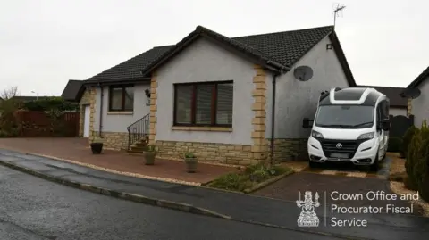 A white motorhome is parked in the driveway of a modern bungalow home 