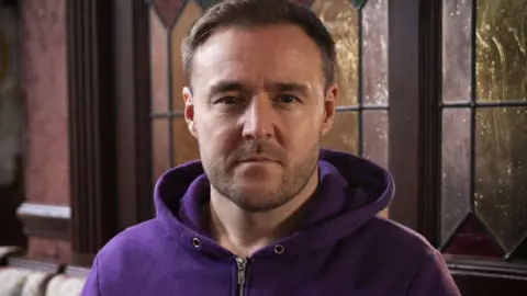 Coronation Street actor wearing purple hoodie