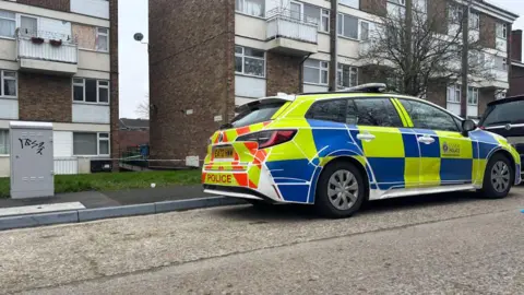 Essex Police There is a police car parked outside the property. It has blue and high-vis yellow flashing on the side. 