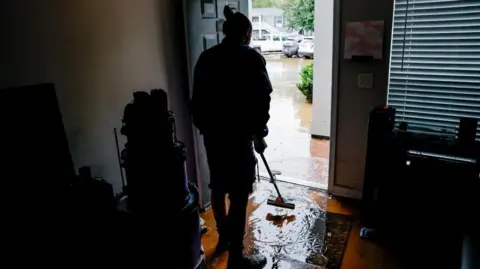 Erik Lesser/EPA-EFE Peachtree Park Apartments resident Andrea Palese begins cleaning up