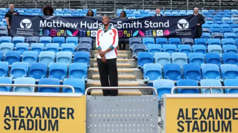 Getty Images Matthew Hudson-Smith poses at Alexander Stadium in front of a banner reading "Matthew Hudson-Smith Stand"