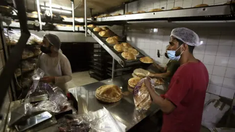 AFP Bakers package workers package freshly-produced bread coming off a production line at an automated bakery in Lebanon"s capital Beirut (1 July 2020)