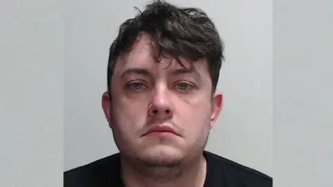 Police Scotland a police mugshot of a man with brown hair wearing a black t-shirt