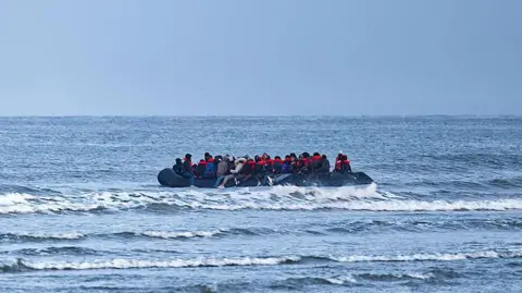 A boat in the English Channel with people on it, many wearing orange life jackets.