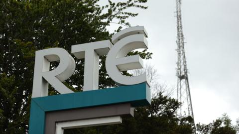 A sign of the RTÉ broadcaster logo, with a tree in the background