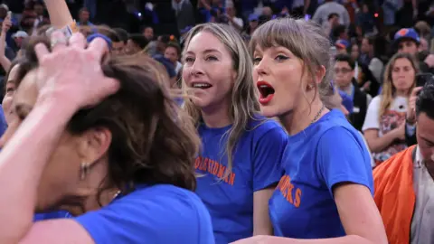 Este Haim and Taylor Swift react after the New York Knicks defeated the San Antonio Spurs