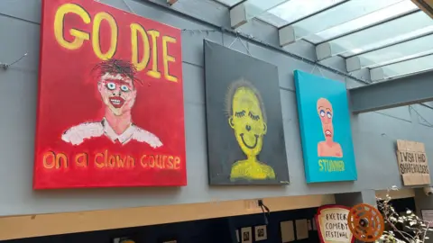 Three pieces of art. One reads "Go die on a clown course" with a picture of an ugly clown.