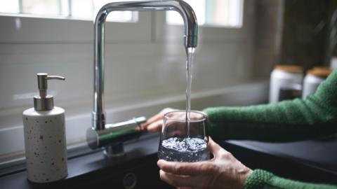 A stock image of a glass of water being filled from a tap