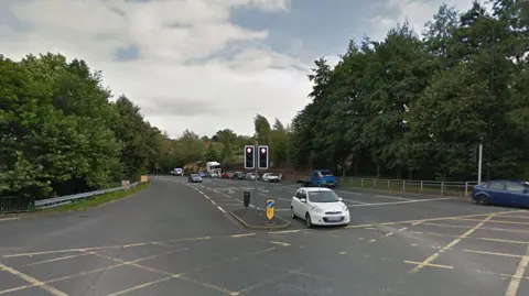 Yellow box junction at Central Park Way, Wigan, on a dry, clear day showing traffic on the right. The traffic light is on red. 