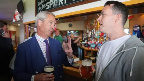 PA Media Nigel Farage and James McMurdock drinking a pint in a pub
