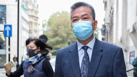 Reuters A man wearing a suit and a face mask as he walks next to a court