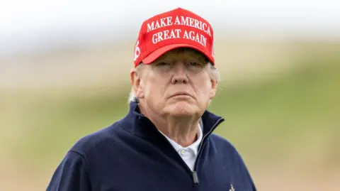 Getty Images US President Donald Trump with Turnberry course in the background. He is wearing a red Make America Great Again cap.