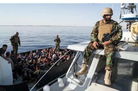 Getty Images A Libyan coast guardsman watches over an operation to rescue illegal immigrants attempting to reach Europe