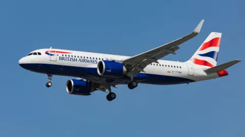 A British Airways Airbus A320 Neo in flights across a bright blue sky. It's landing gear is lowered.