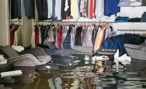 Brendan Digney Clothing and furniture float on the floodwater in McCartan's men's clothing shop in Newry