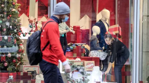 PA Media A man in a mask walks past a shop in Manchester