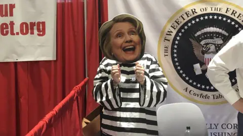 A woman at Cpac is dressed as Hillary Clinton in prison garb.