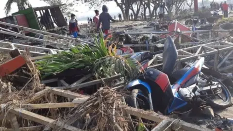 Reuters People walk among debris in Palu. Photo: 29 September 2018