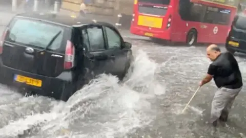 ANDREWSVISUAL via BBC Man sweeping water