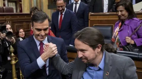 Getty Images Pedro Sánchez clinches victory with Podemos leader Pablo Iglesias, 7 Jan 20