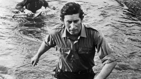 Royal Navy/Ministry of Defence Crown/PA Media King Charles III back when he was the Prince of Wales in 1974 wades through waist-deep water during training at the Commando Training Centre in Devon.