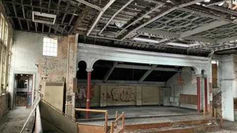 Sheffield City Council The inside of the building with stripped peeling walls, ceiling rafters and a stage.