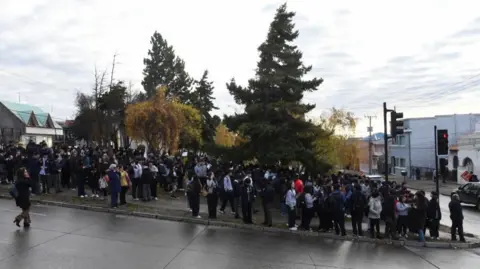A large group of people stood around tress outside in Punta Arenas.