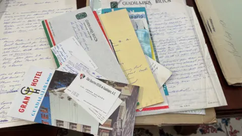 Edd Smith/BBC A collection of pieces of paper, documents and business cards spread on a table.