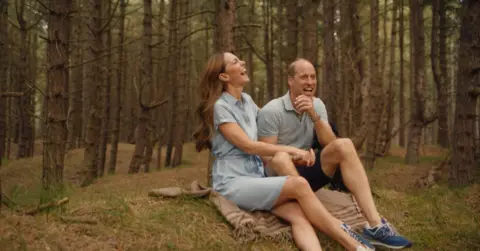 Will Warr/Kensington Palace The Prince and Princess of Wales laugh while in a forest scene sitting on a blanket 