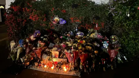 Yilmaz family An area on a street with many flowers and candles in tribute to Cemal Yilmaz